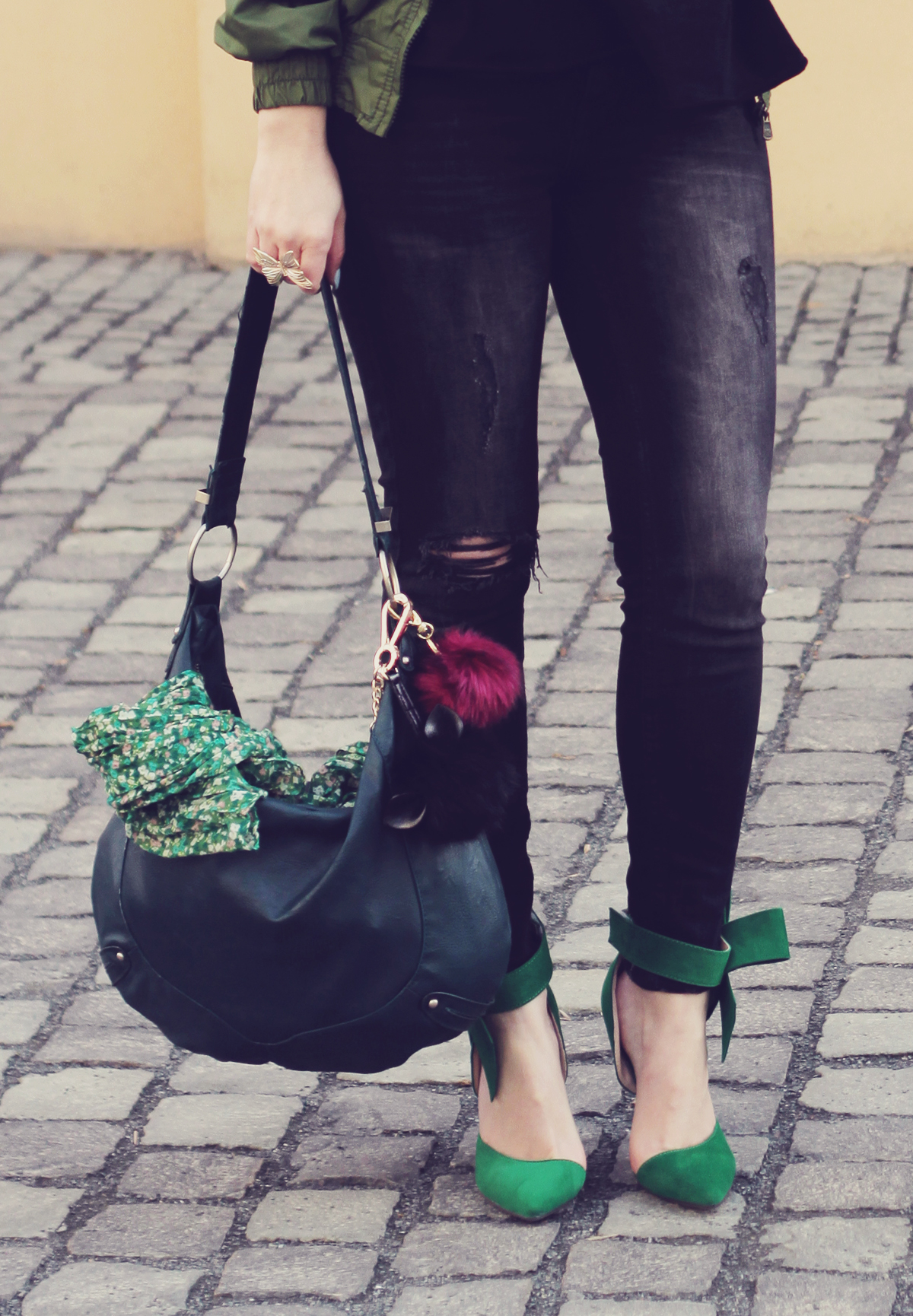 green heels and shoulder bag with pom-poms